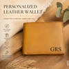 Brown leather wallet with 'GRS' initials on a wooden surface with decorative elements.