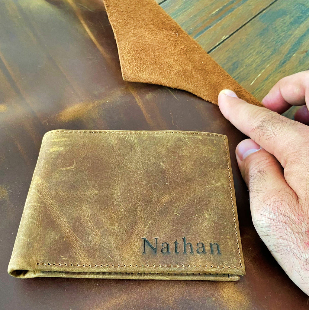 Brown leather wallet with 'Nathan' engraving on a wooden surface, labeled as 100% full grain leather.