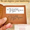 A hand holds a brown leather wallet showing two handwritten message inserts on white paper. Text at the top says 'We can engrave your handwriting' and a contact card appears at the bottom right.