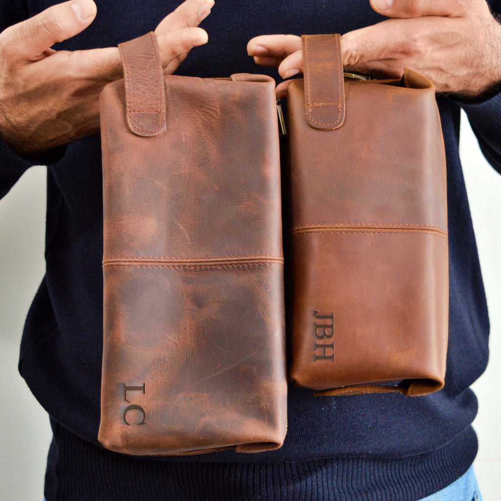 Two brown leather pouches held by a person against a neutral background