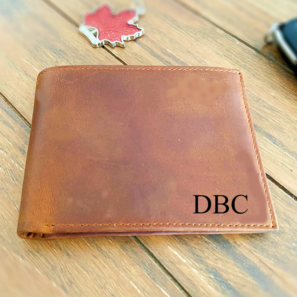 Brown leather wallet with 'DBC' initials on a wooden surface