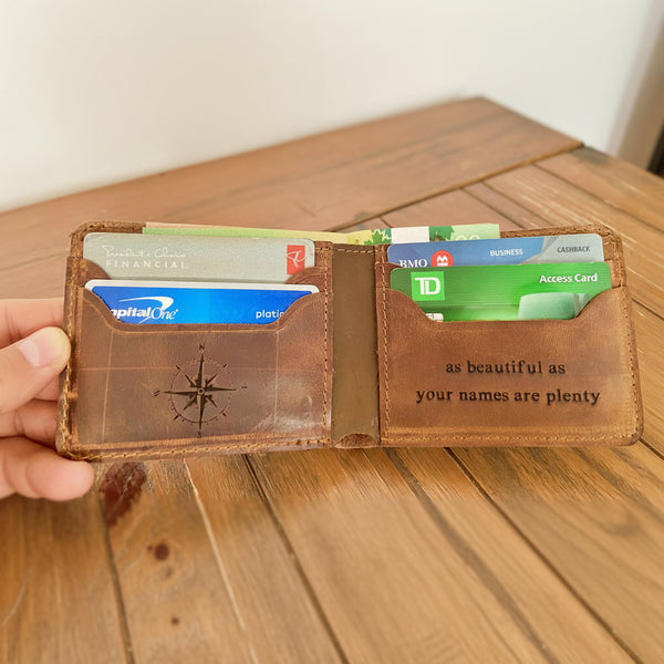 Brown leather wallet with engraved text and credit cards on a wooden surface